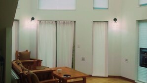 A spacious room with a high ceiling, wooden furniture, and large windows with blinds. - Seolrem 9 (Yangyang)