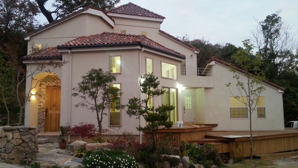 A two-story house with a stone entrance, multiple windows, and a wooden deck. - Seolrem 9 (Yangyang)