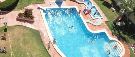 An aerial view of a swimming pool area with multiple pools and sun loungers.
