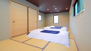 Quarto de hotel com duas camas, tatames, uma porta de correr e uma janela.