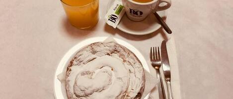 A plate with a pastry, a glass of orange juice, and a cup of coffee on a table.