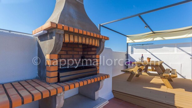 An outdoor barbecue area with a brick oven, a wooden table, and a white canopy. - Obelisc-3, 3 DB ground-floor apartment near the beach. (Can Picafort)