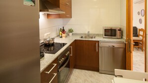 A compact kitchen with a refrigerator, stove, oven, microwave, and dishwasher. - Obelisc-3, 3 DB ground-floor apartment near the beach. (Can Picafort)
