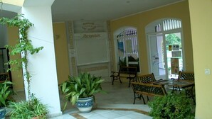 A reception area with a tiled floor, potted plants, and a reception desk. - APCOSTAS San Antonio / Two Dedrooms (Alcoceber)