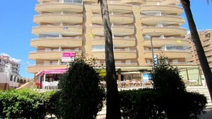 Un hotel de varios pisos con balcones, un restaurante y terraza.