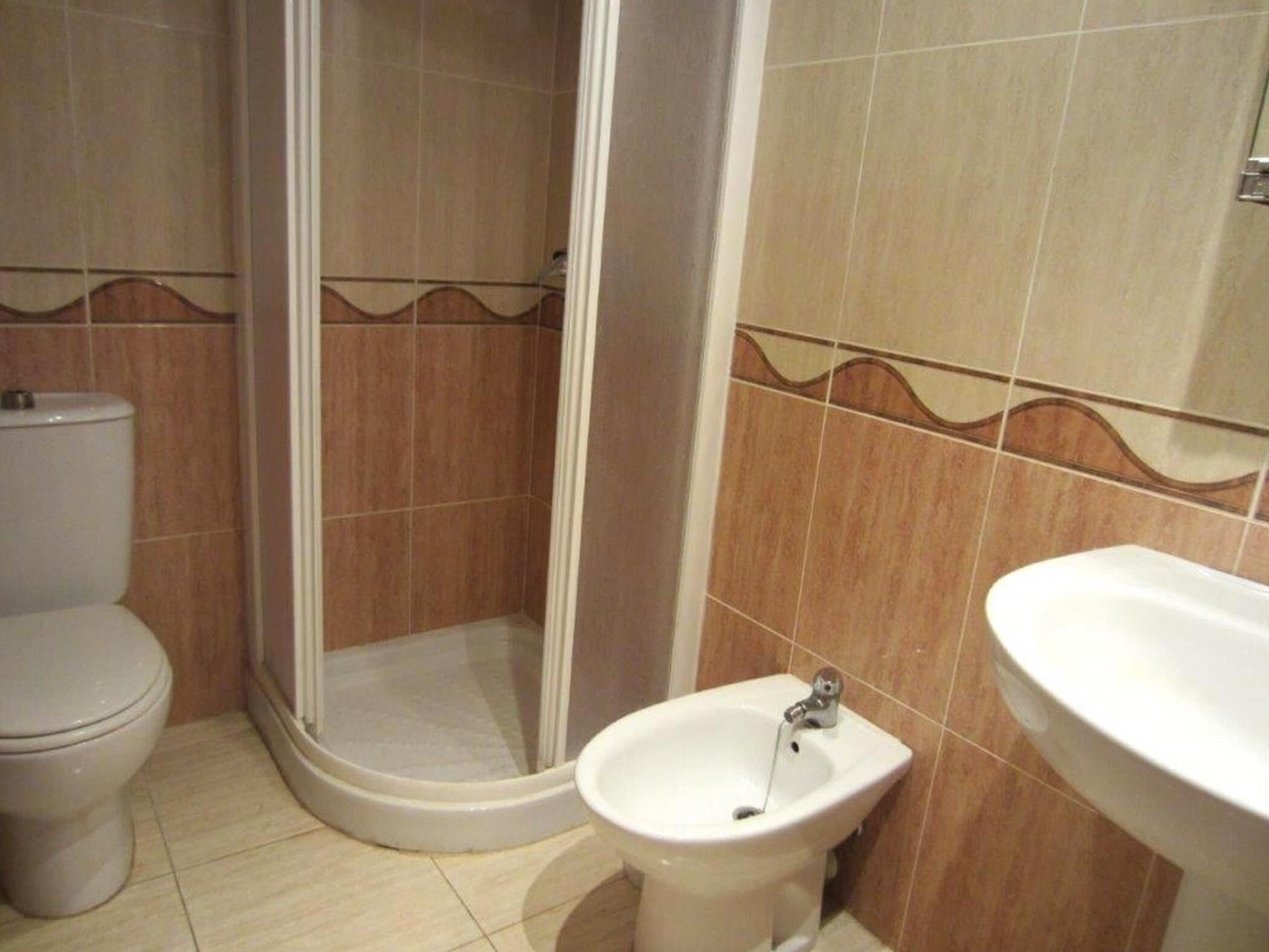 Une salle de bain comprenant des toilettes, un espace douche et un bidet.