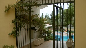 A gated outdoor area with a pool, potted plants, and a white building in the background. - APCOSTAS San Antonio / Three Dedrooms (Alcoceber)