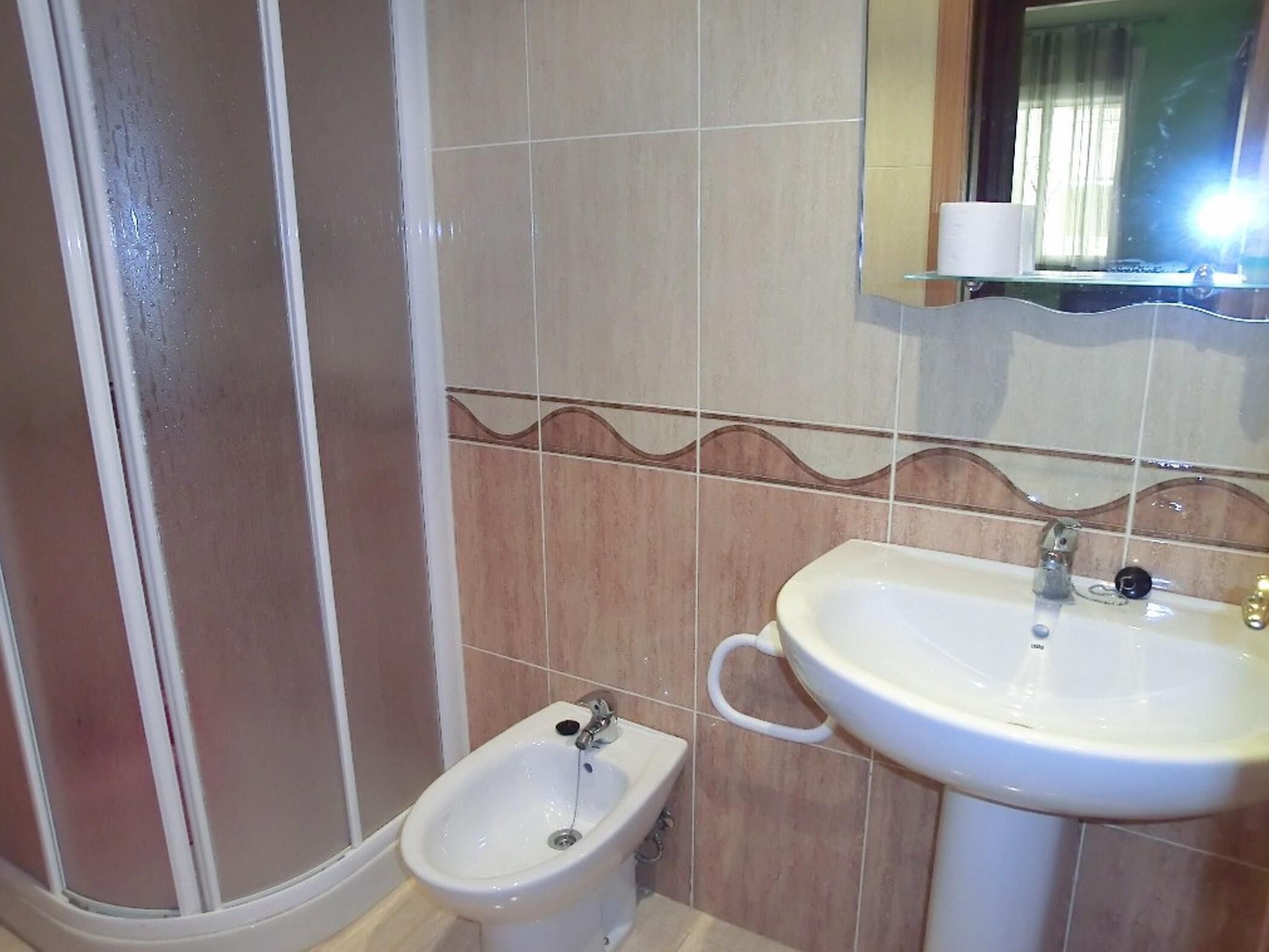 A bathroom with a bidet, a sink, and a mirror.