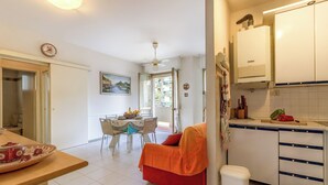 A compact kitchen with white cabinets, a dining area with a table and chairs, and a red sofa. - Mare 7 250m From Sea in Marina di Massa, Marina di Massa, Italy (Marina di Massa)
