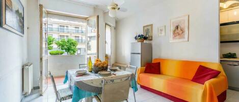 A dining area with a table set for two, a sofa, and a ceiling fan.