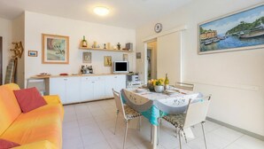 A dining area with a table set for two, a sofa, and a kitchen in the background. - Mare 7 250m From Sea in Marina di Massa, Marina di Massa, Italy (Marina di Massa)