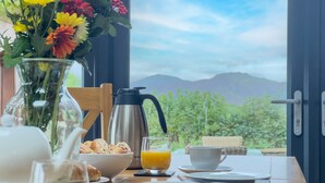 A breakfast table with a vase of flowers, a coffee pot, croissants, and orange juice. - Lake View, luxurious home with 2 ground floor bedrooms, stunning Lake Ullswater views. (Penrith)