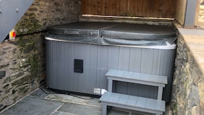 Un bain à remous avec des marches, un mur en pierre et un escalier en métal.