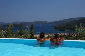 Une piscine avec vue sur la mer et les collines.