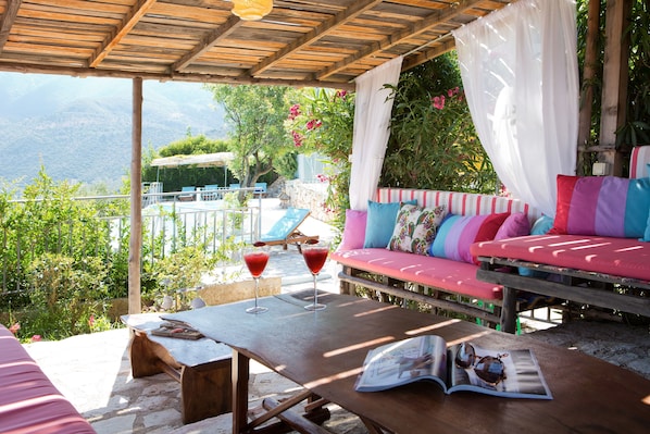 Un espace extérieur abrité avec une table en bois, deux boissons et un magazine.