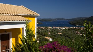 A yellow building with a tiled roof overlooking a coastal town and the sea. - Luxury villa overlooking the sea with private pool-Villa Rose (Lefkada)
