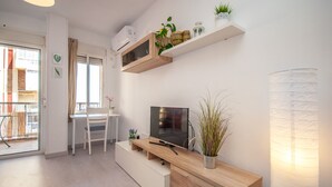 Ein modernes Wohnzimmer mit Fernseher, Holzschrank und Zierpflanzen.