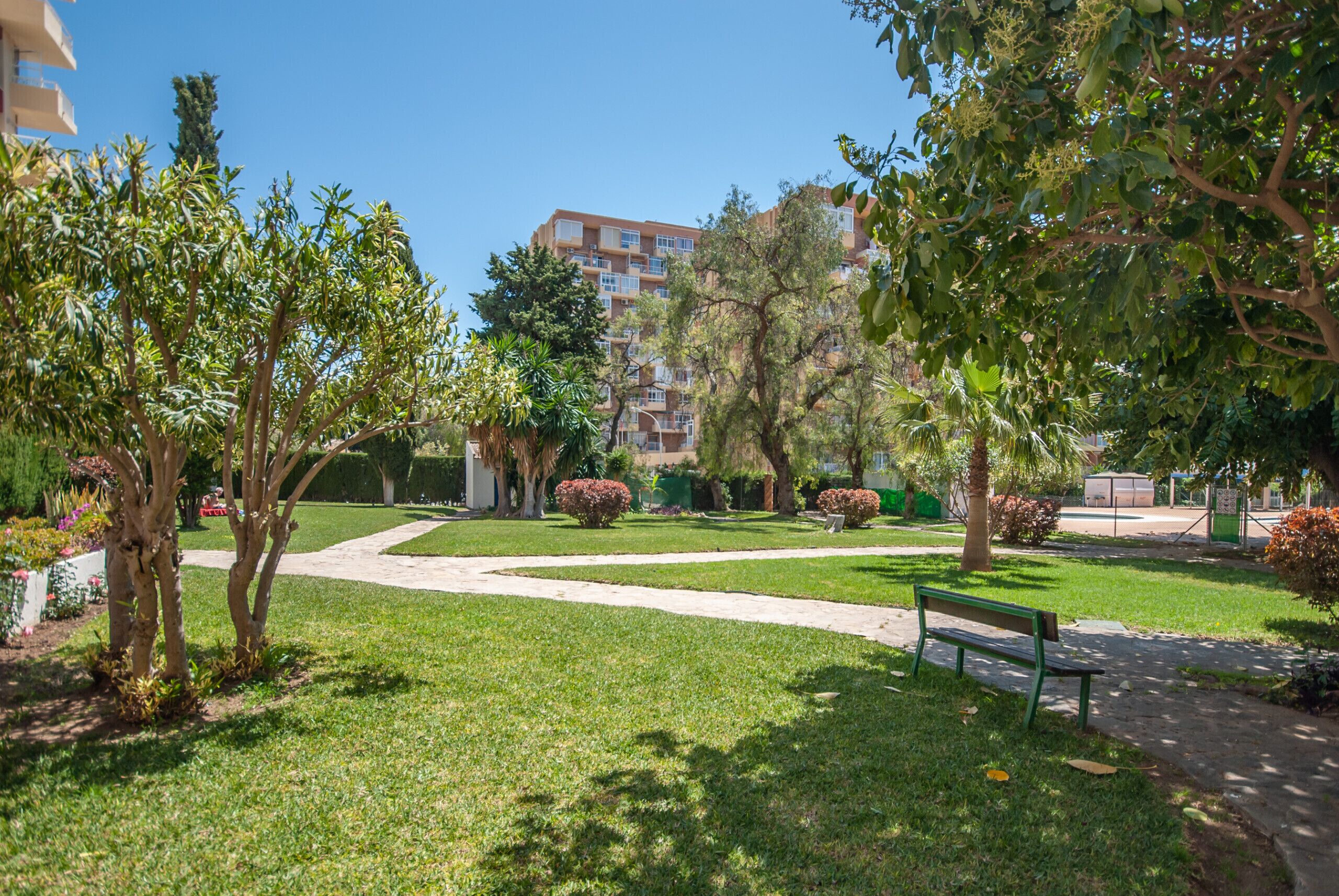 A well-maintained garden with a pathway, benches, and a building in the background.