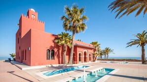 Ein Gebäude mit einem Turm, Palmen und einem Pool mit Wasserspielen.