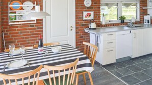Una cucina con un tavolo a righe, sedie di legno, una porta bianca e un muro in mattoni.