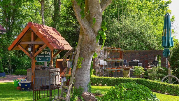 A rustic wooden structure with a sloped roof, a signboard, and a small table with chairs.
