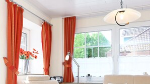 A living room with a sofa, armchair, and a table with a vase of flowers. - Vacation apartment Strandkrabbe - Haus an der Burg (Werdum)
