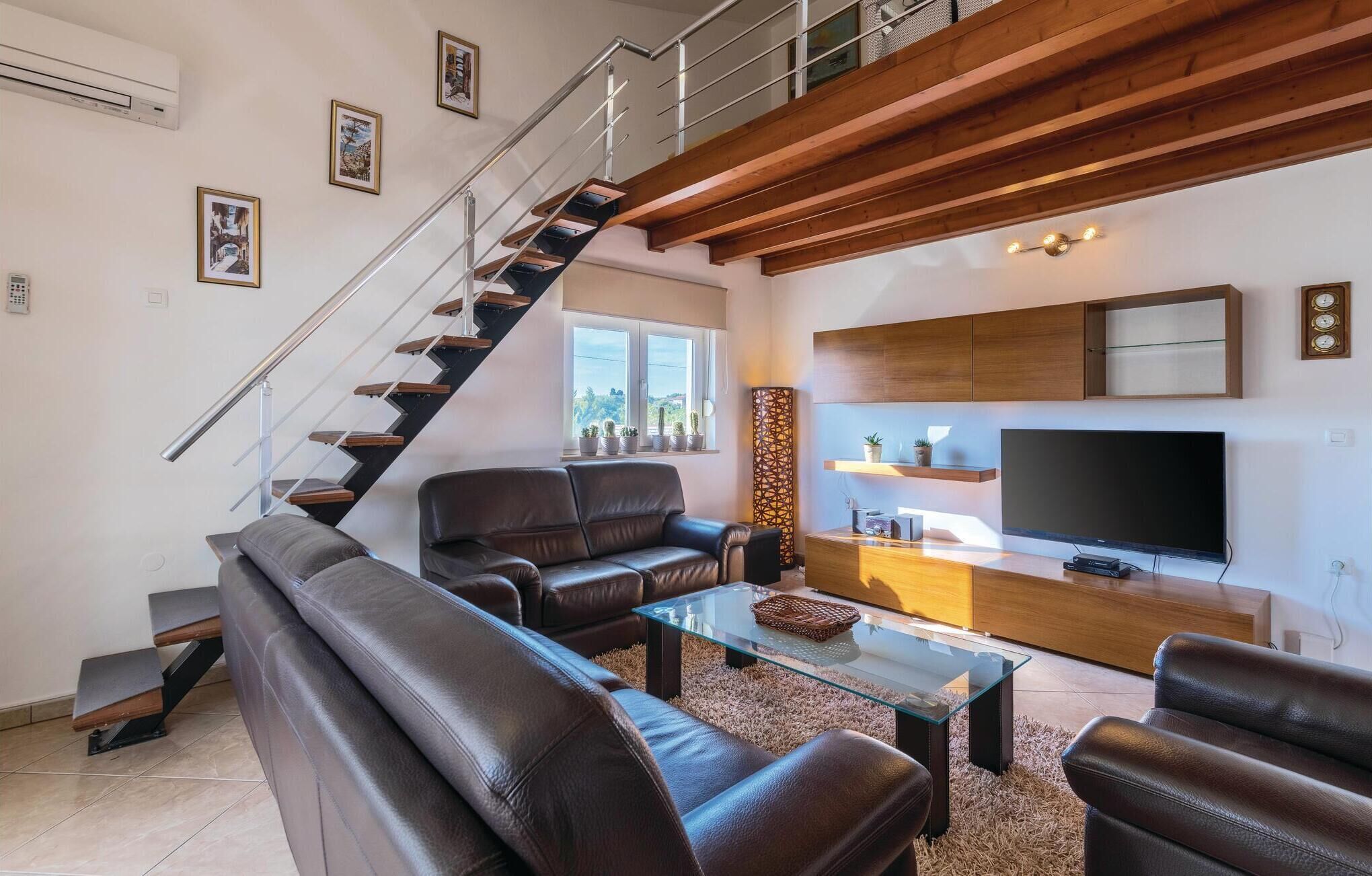 Un salon moderne avec un escalier, des canapés en cuir, une table basse en verre, un téléviseur à écran plat et un élément décoratif mural.