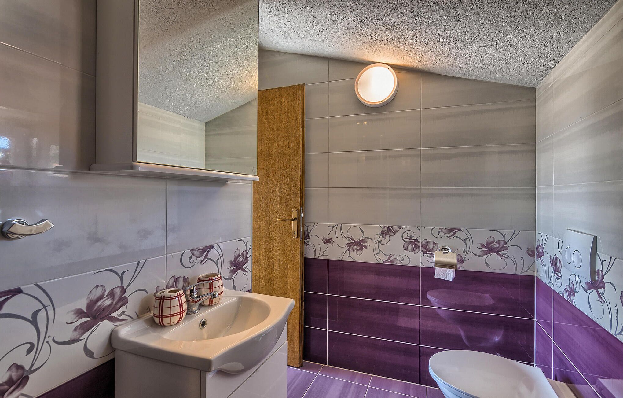 A bathroom with a sink, mirror, and toilet.