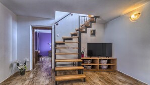 A modern interior with a wooden staircase, a flat-screen TV, and a wooden bench. - Lovely home in Liznjan (Liznjan)