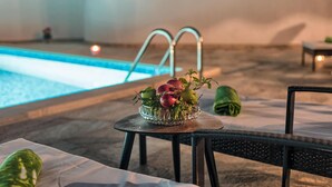 A poolside area with a glass table holding a fruit bowl, a chair, and a small table with a candle. - Lovely home in Liznjan (Liznjan)