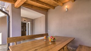 A wooden dining table with a bench, a fruit bowl with fruit and a glass of orange juice, and a wall-mounted light fixture. - Lovely home in Liznjan (Liznjan)