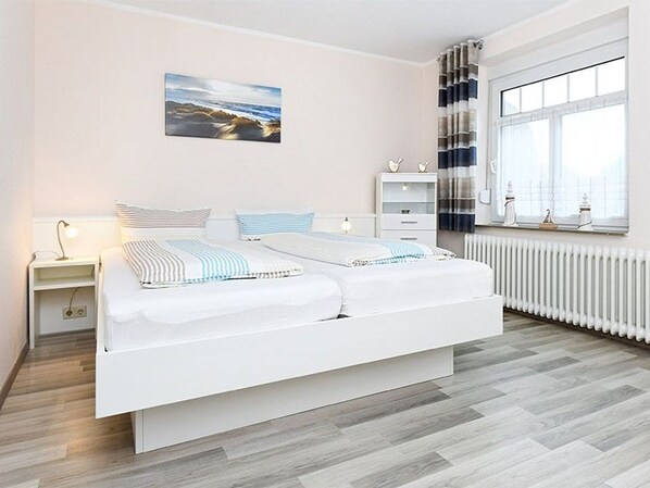 Une chambre moderne avec un grand lit, des tables de chevet, un radiateur et une fenêtre avec des rideaux.