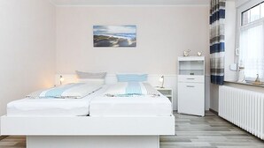 Un dormitorio moderno con una cama grande, mesitas de noche, un radiador y vistas al exterior.