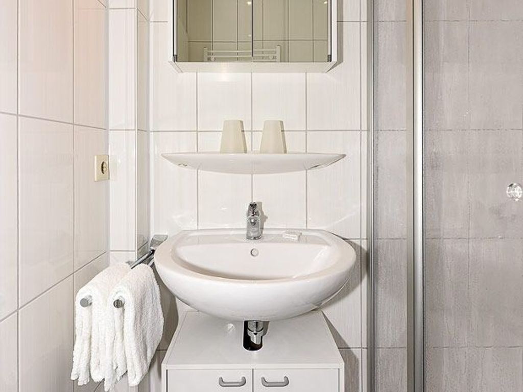 A bathroom with a white sink, a mirror above it, and a towel hanging on a rack.