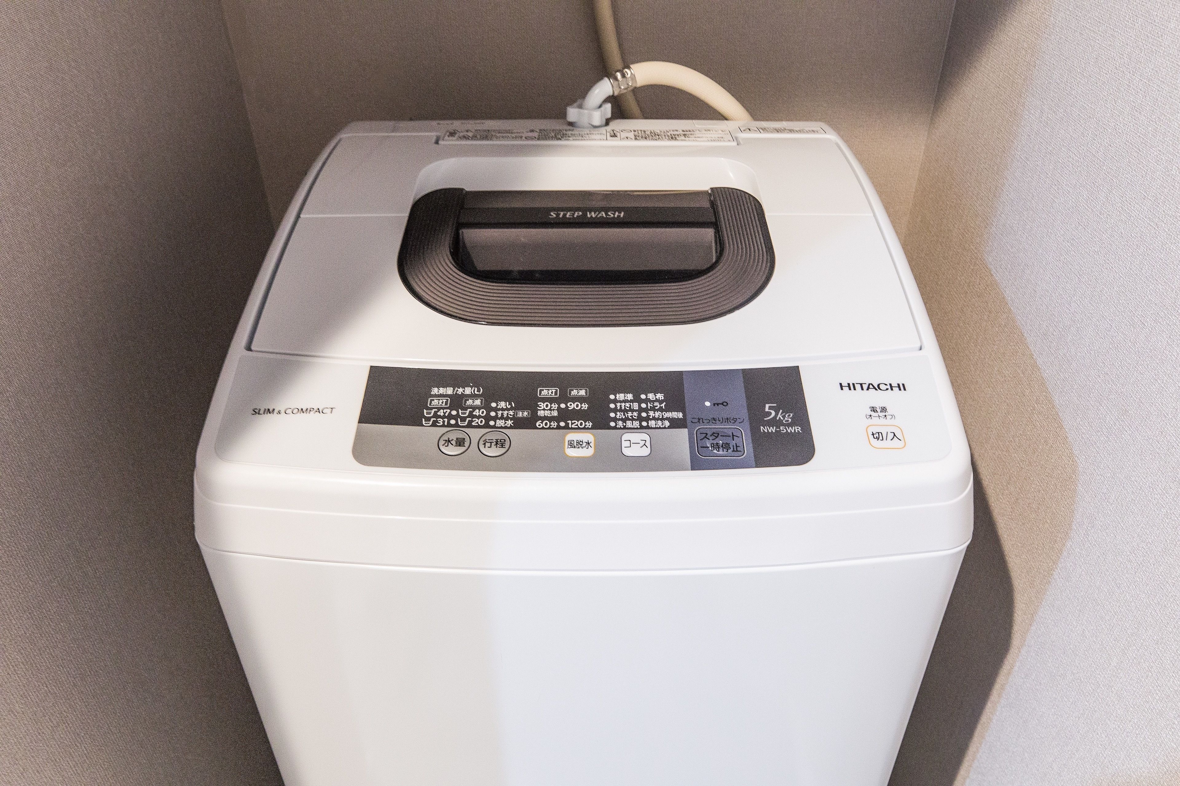 A white, compact, slim washing machine with a step wash feature and a 5kg capacity.