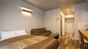 Ein Hotelzimmer mit einem großen Bett, einer Couch, einem kleinen Tisch und einem durchgegangenen Tür erkennbaren Badezimmer.