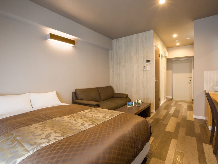 Ein Hotelzimmer mit einem großen Bett, einer Couch, einem kleinen Tisch und einem durchgegangenen Tür erkennbaren Badezimmer.