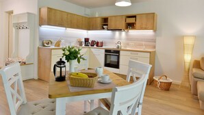 Une cuisine moderne avec des meubles de rangement en bois, une table à manger avec des chaises et une machine à café.