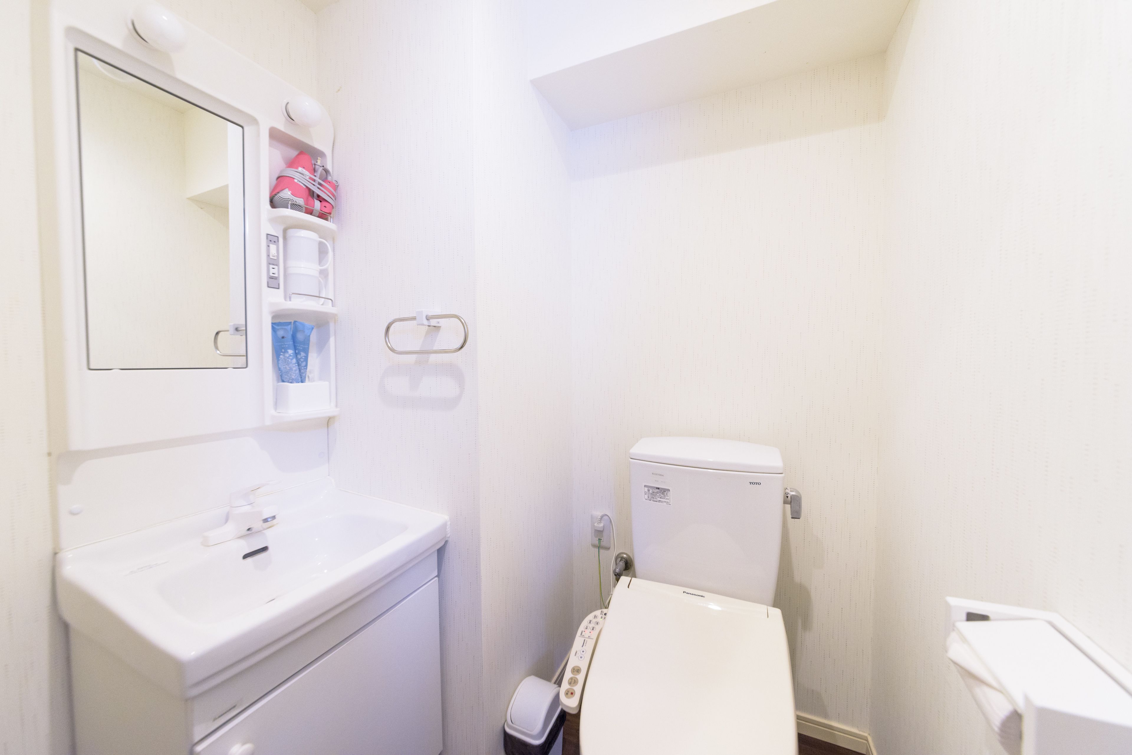 A small, white bathroom with a sink, mirror, and toilet.