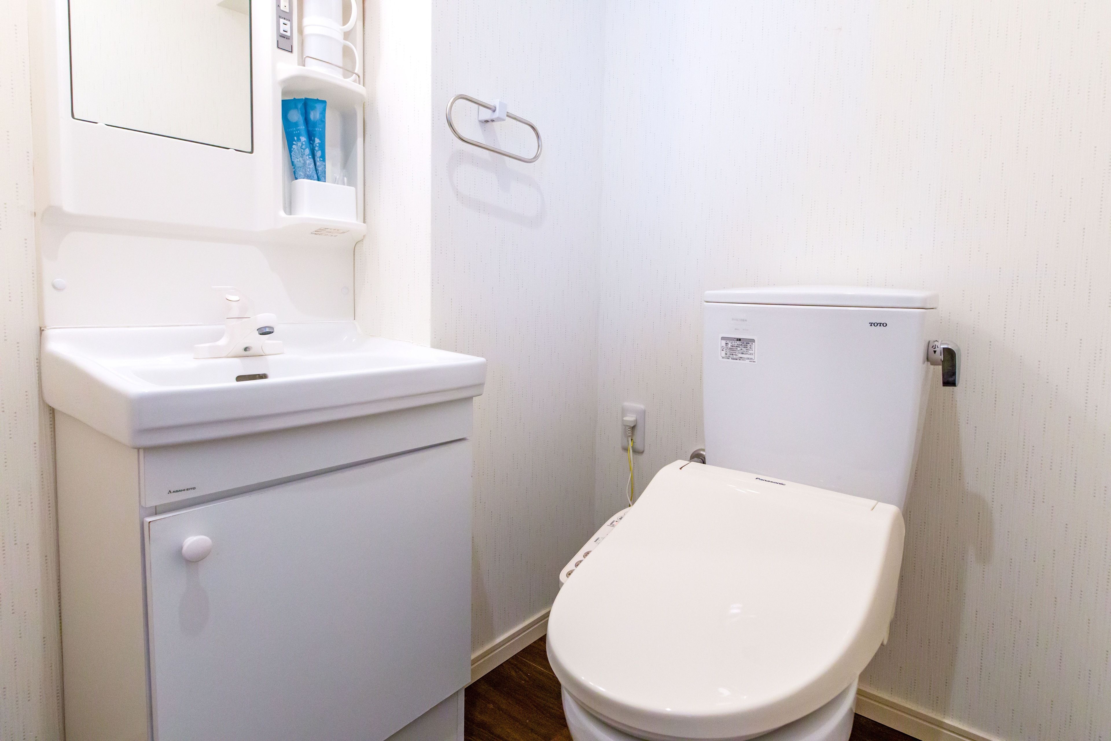 Un baño pequeño y blanco con inodoro, lavamanos y espejo.