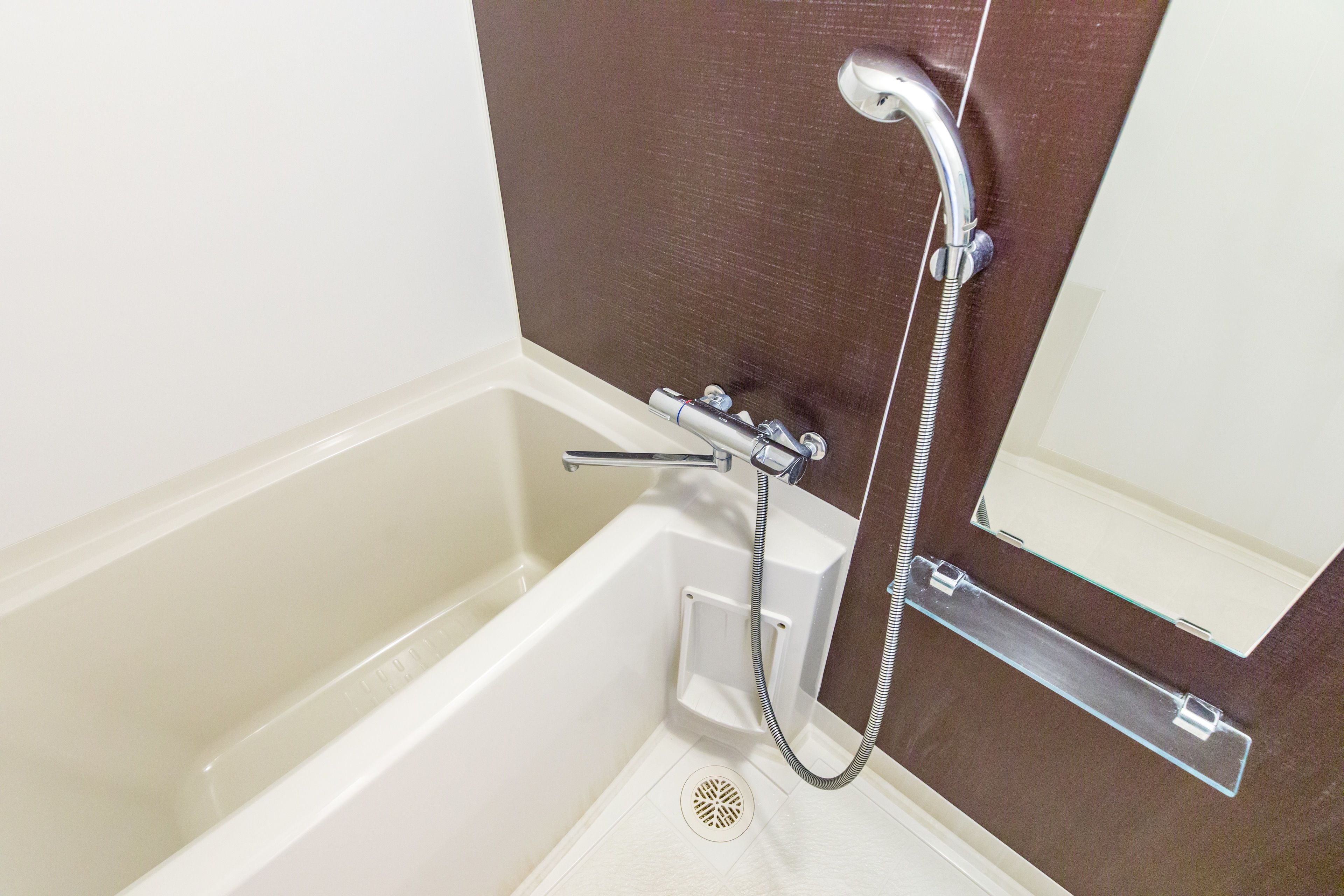 A bathroom with a bathtub, a shower, and a mirror.