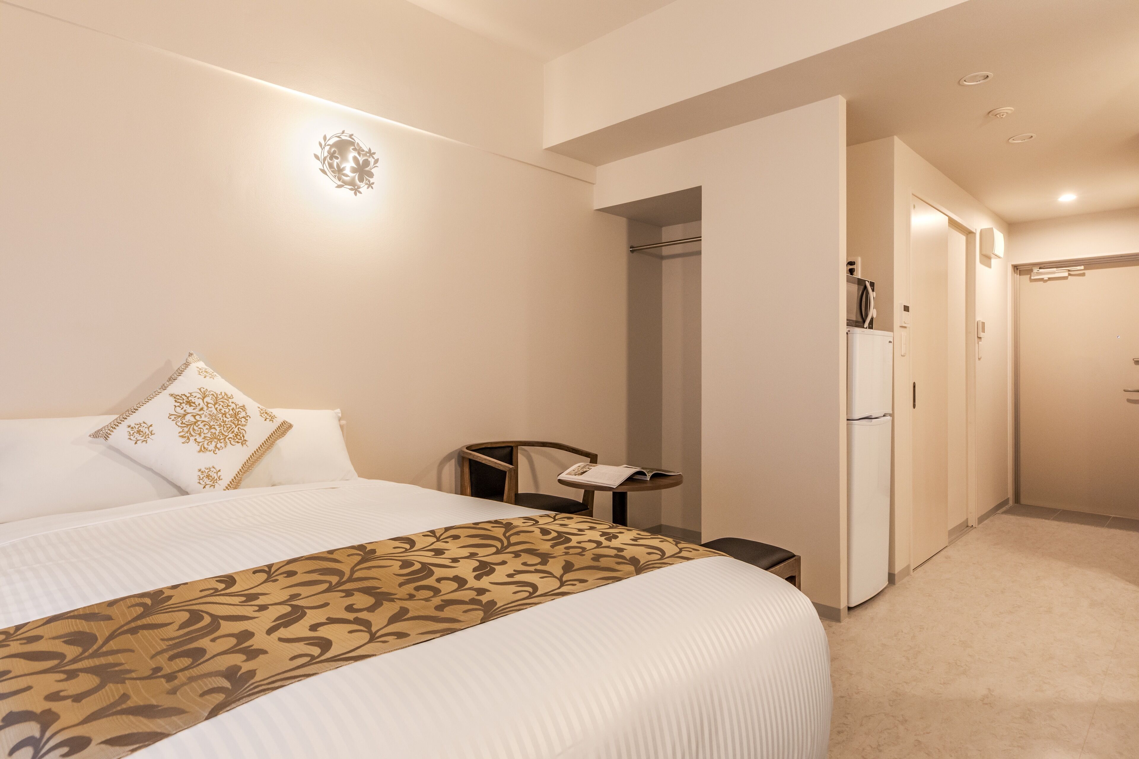 Habitación de hotel con una cama grande, un escritorio, una silla y un armario.