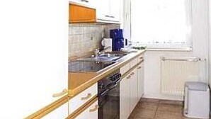 Een keuken met witte kastjes, een fornuis en een spoelbak.