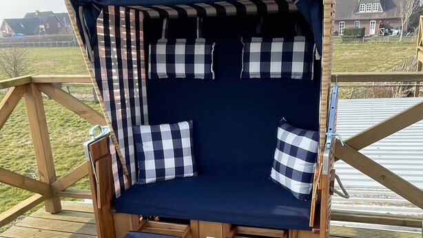 A wooden deck with a blue cushioned seating area featuring checkered pillows.