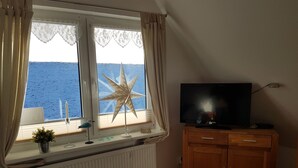 A room with a large window, a star decoration, a television, and a wooden cabinet.