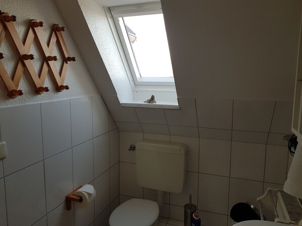 A small, basic bathroom with a toilet, a sink, and a window. - Apartment 1 at the Aussendeich Nordstrand North Frisian Islands (Nordstrand)