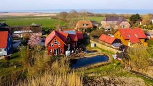 Ein ländliches Dorf mit traditionellen Häusern, einem kleinen Teich und freiem Blick auf das Meer.