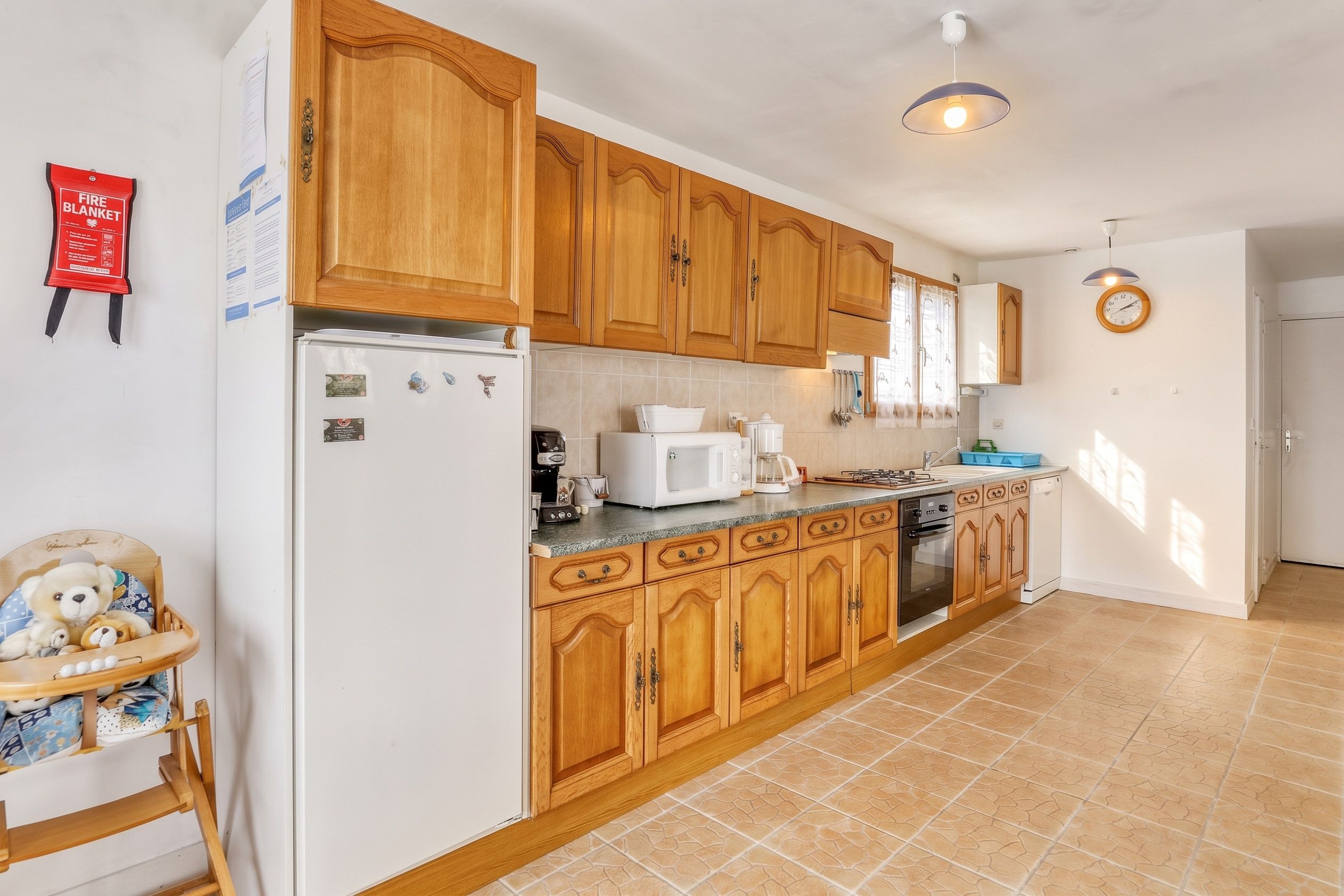 A kitchen with wooden cabinets, a refrigerator, a microwave, a coffee maker, and a sink.