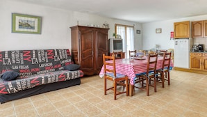 A living room with a sofa, a dining table with chairs, a kitchen area, and a large wooden cabinet. - Homerez - House - Nevez, Enclosed (Nevez)