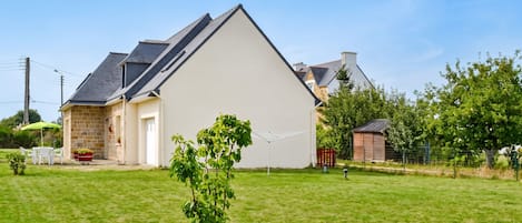 A residential property with a large white house, a small shed, and a well-maintained lawn.